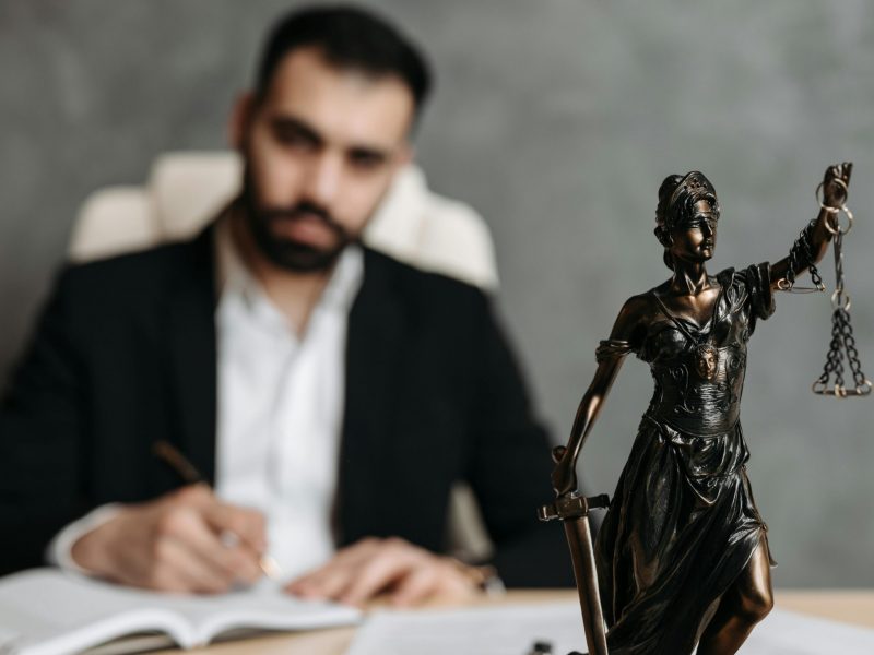 Rechtsanwalt mit Justitia Figur.